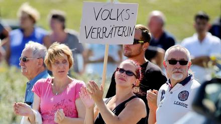 Viele waren es Reportern zufolge nicht - aber einige Anwohner buhten Bundeskanzlerin Angela Merkel bei ihrem Besuch in Heidenau aus. Auf einem Plakat wurde die Kanzlerin als "Volksverräterin" bezeichnet.