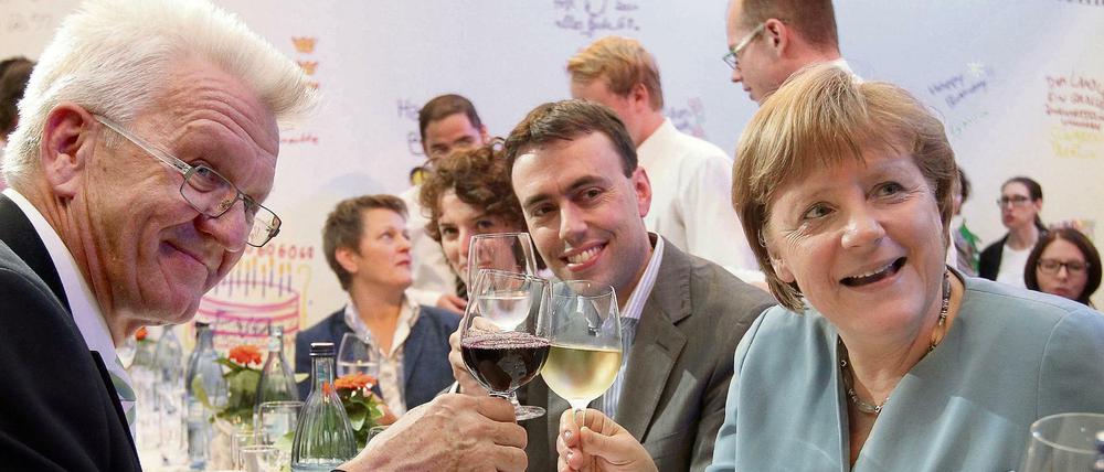 Baden-Württembergs Ministerpräsident Winfried Kretschmann (Die Grünen), sein Finanzminister Nils Schmid (SPD) und Bundeskanzlerin Angela Merkel (CDU.) stoßen beim Sommerfest des Landes Baden-Württemberg in Berlin mit Wein an.  