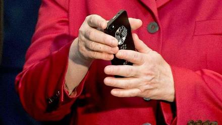 Auf der Computermesse CeBit begutachtet Merkel ein Handy mit Bundesadler. Dass ihr eigenes abgehört werden könnte, hatte sie sicher nicht vermutet.