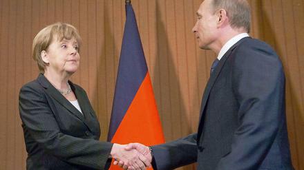 Kanzlerin Angela Merkel und der russische Präsident Wladimir Putin reichen einander die Hand. 