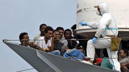 Diese Flüchtlinge haben Glück gehabt. Ein Militärschiff hat sie rechtzeitig aus dem Mittelmeer gezogen. Nun warten Sie darauf, in Italien an Land zu gehen. 