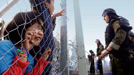 Gestoppt.  Ein Flüchtlingsmädchen weint und umklammert einen Zaun im mazedonischen Gevgelija. Am dortigen Grenzübergang kommen nur noch syrische und irakische Flüchtlinge durch.