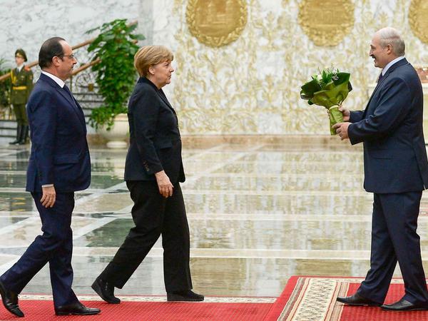 Der Weißrussische Präsident Alexander Lukaschenko empfängt Angela Merkel mit einem Blumenstrauß. Francois Hollande ging vorerst leer aus.