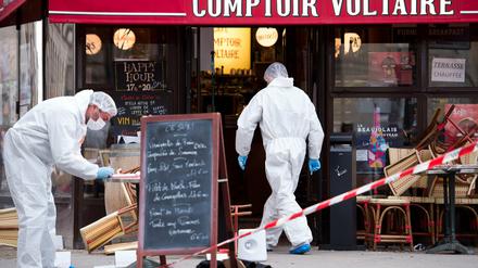 Polizisten in Schutzanzügen sichern am Samstag vor dem Cafe Comptoir Voltaire in Paris Spuren. 
