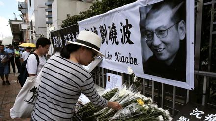 Eine Frau legt am in Hongkong Blumen für den verstorbenen chinesischen Friedensnobelpreisträger Liu Xiaobo nieder. 