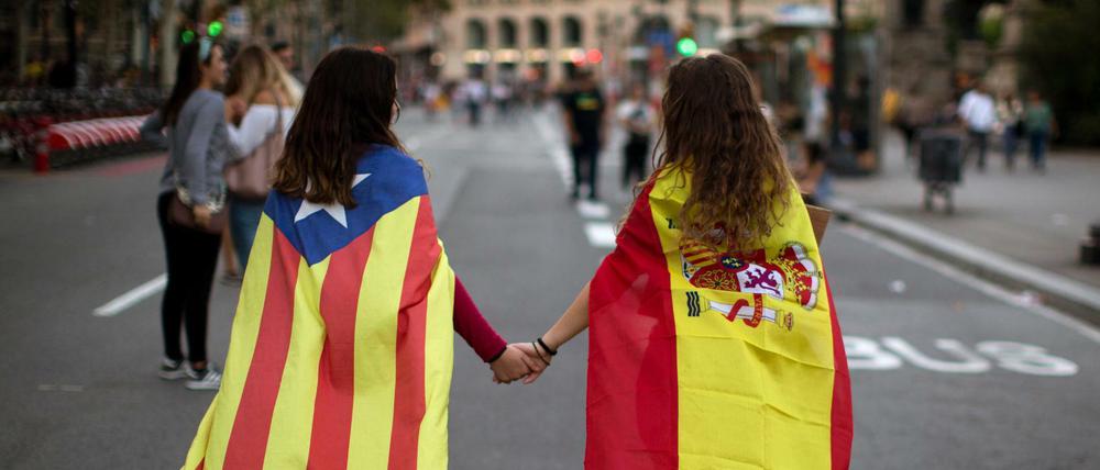 Hoffen auf Eintracht: Zwei junge Frauen, in die spanische Nationalflagge (rechts) sowie die katalanische Flagge "Estelada" gehüllt 