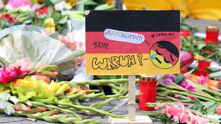 Ein Aufsteller in den deutschen Nationalfarben mit der Aufschrift "#prayforgermany" und "Warum?" steht vor dem Olympia-Einkaufszentrum in München, einen Tag nach einer Schießerei mit Toten und Verletzten, inmitten von Blumen zum Gedenken an die Opfer. Die tödlichen Schüsse hat ein 18-jähriger Deutsch-Iraner abgegeben. 