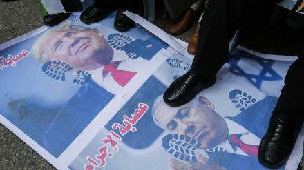 Protest gegen den Nahost-Plan: Demonstranten stehen mit Schuhen auf Fotos von Trump und Netanjahu 