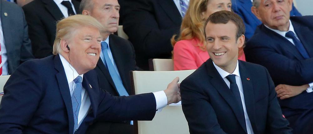 Der französische Präsident Emmanuel Macron (r) lacht mit US-Präsident Donald Trump während der Parade auf dem Champs Elysees.