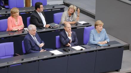 Horst Seehofer (CSU), Olaf Scholz (SPD) und Angela Merkel (CDU) sitzen nebeneinander im Bundestag.