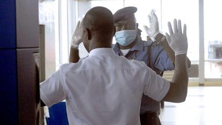 Mit Mundschutz und Handschuhen überprüft ein Mitarbeiter des Flughafens von Lagos einen Passagier.