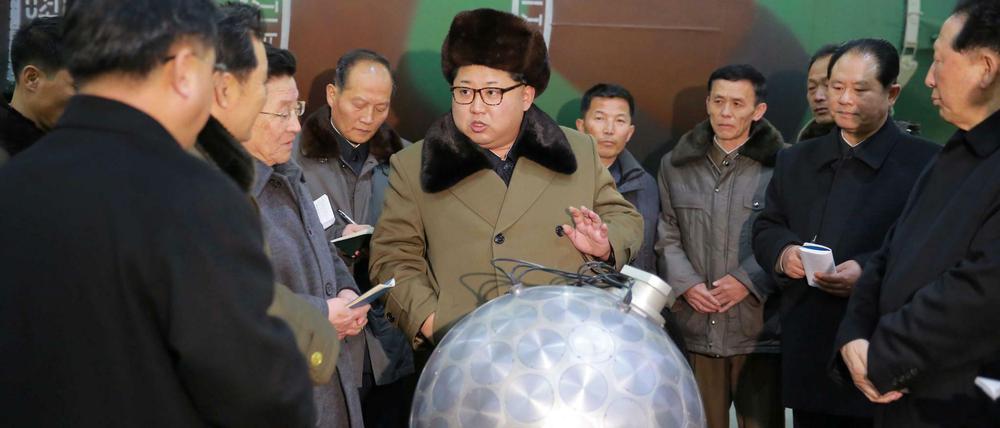 Nordkoreas Machthaber Kim Jong Un mit einem angeblichen Atomsprengkopf, aus dem einige Kabel ragen.