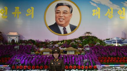 Eine Frau in Uniform vor einem Portrait von Kim Il Sung in Nordkorea. 