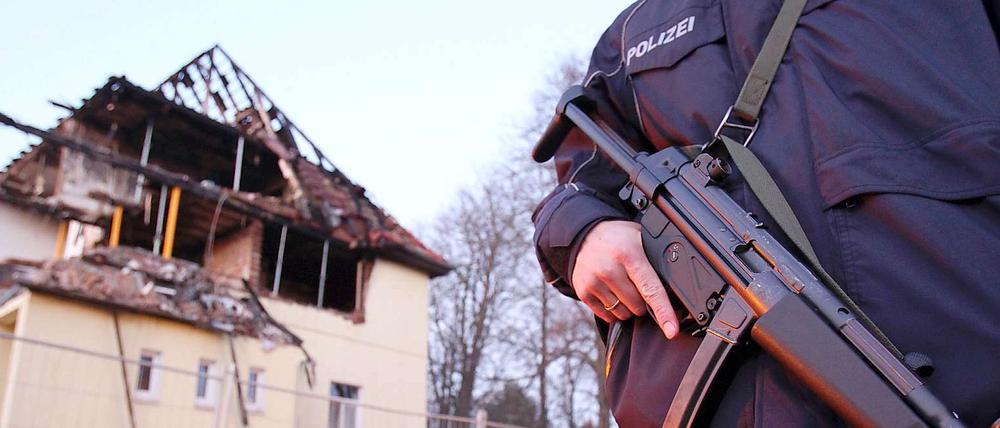 Ein Polizist mit Maschinenpistole steht in Zwickau vor dem durch eine Explosion zerstörten Haus, das von den NSU-Mitgliedern Uwe Mundlos, UweBöhnhardt und Beate Zschäpe bewohnt wurde 