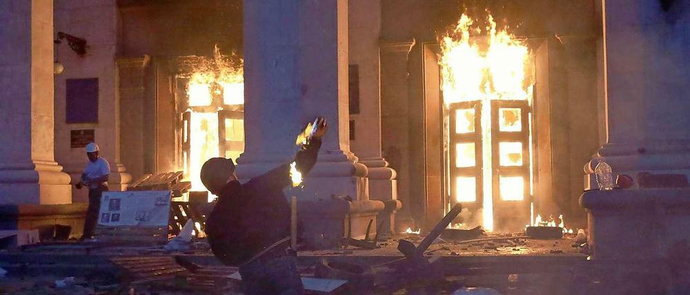 Ein Demonstrant schmeißt einen Brandsatz auf das bereits brennende Gewerkschaftshaus in Odessa.