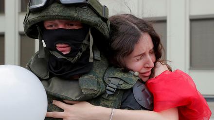 Eine Frau umarmt einen Soldaten vor dem Regierungsgebäude in Minsk. 