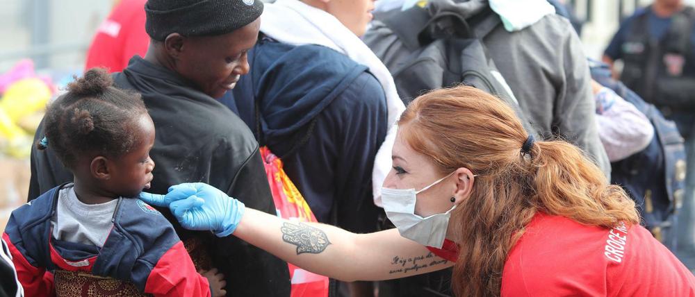 Palermo, Ende Juni: Eine Mitarbeiterin des italienischen Roten Kreuzes nimmt Migranten in Empfang.