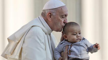 Papst Franziskus küsst ein Kind, als er mit dem Papamobil auf dem Petersplatz ankommt, um seine wöchentliche Generalaudienz im Vatikan abzuhalten. 