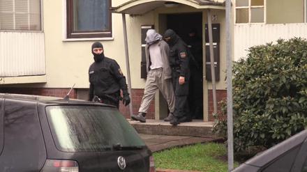 Polizisten führen am Dienstag in Bremen einen Mann aus einem Haus. Die Polizei hat mehrere Wohnungen und Geschäfte von Salafisten in Bremen durchsucht.