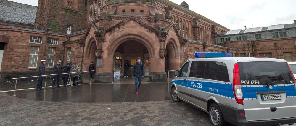 Ein Polizeifahrzeug und bewaffnete Polizisten stehen vor dem Hauptbahnhof in Gießen.