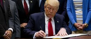 Unterschriften, die bis nach Deutschland wirken. US-Präsident Trump bei der Arbeit. 