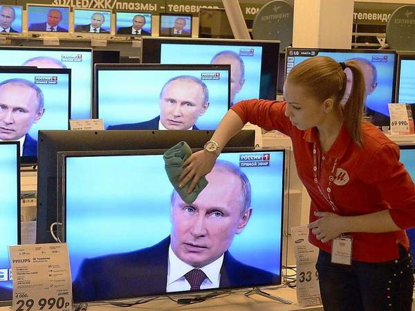 Steht Putin etwa schon der Schweiß auf der Stirn? Eine Angestellte in einem Moskauer Elektronikgeschäft wischt die Fernsehmonitore ab, die während der Fragestunde nur ein Motiv kennen. 