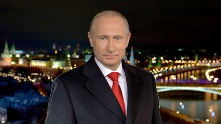 Der russische Präsident Wladimir Putin bei seiner Neujahrsansprache.  Im Hintergrund ist Moskau bei Nacht zu sehen.