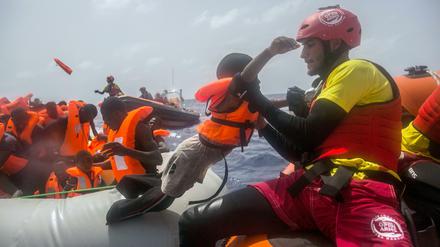 Ein Mitarbeiter der spanischen NGO «Proactiva Open Arms» hebt am 25.07.2017 vor der libyschen Küste ein Kind vom einem Flüchtlingsboot. 
