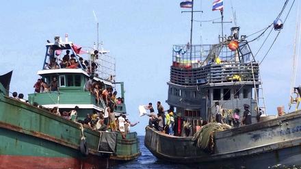 Bootsflüchtlinge aus Myanmar und Bangladesch erhalten Nahrungsmittel und Wasser von einem thailändischen Fischerboot.