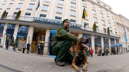 Bitte recht freundlich. Polizist mit Hund vor dem Tagungshotel Bayerischer Hof in München.