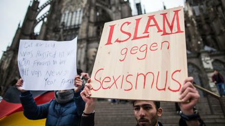 Ein Mann aus Syrien verurteilt mit einem Plakat vor dem Hauptbahnhof und dem Dom in Köln die sexuelle Gewalt der Silvesternacht.