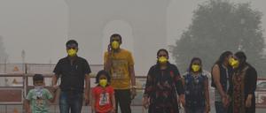Dicke Luft über Neu Delhi: Menschen mit Masken stehen in der Nähe des India Gate im Smog. 
