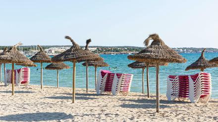 Sonnenliegen und Sonnenschirme an einem leeren Strandabschnitt auf Mallorca.