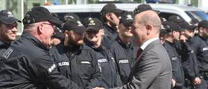 Hamburgs Erster Bürgermeister Olaf Scholz (SPD, M) unterhält sich am Sonntag in Hamburg vor den Messehallen mit Einsatzkräften der Polizei.