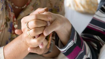 Eine Therapeutin hält im Hospiz St. Martin in Stuttgart die Hand einer todkranken Bewohnerin.