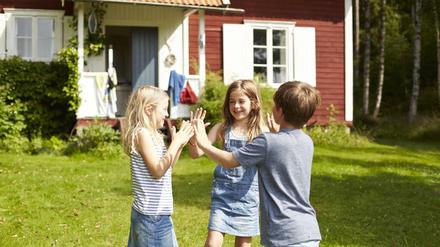Drei Kinder spielen vor einem Haus (Symbolbild).