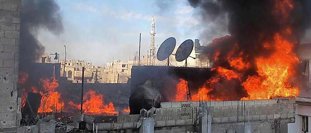 Flammen schlagen aus einem Haus in der syrischen Stadt Homs.