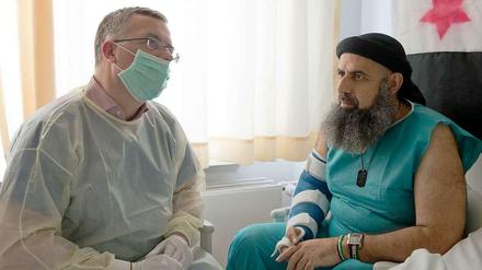 Markus Löning (links) erkundigt sich bei Eitham al Abud, einem der 36 Schwerverletzten Syrer, die in Deutschland behandelt werden, nach der Situation im Bürgerkriegsland.