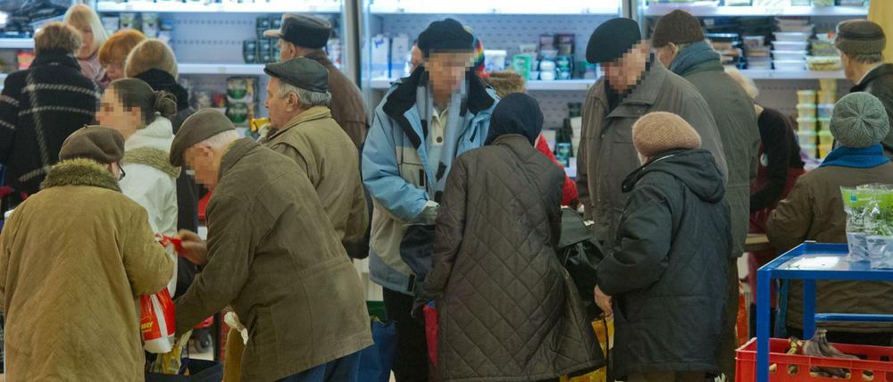 In einer langen Schlange warten Bedürftige in der Tafel der Stephanusgemeinde in Wiesbaden auf die Ausgabe von Lebensmitteln. 