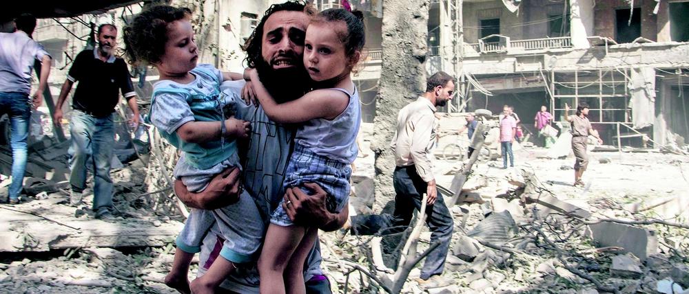 Opfer des Krieges. Ein Vater versucht nach einem Bombenangriff in Aleppo, seine beiden Kinder in Sicherheit zu bringen.