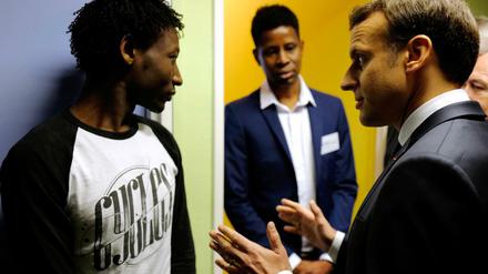Der französische Präsident Emmanuel Macron spricht in einem Flüchtlingszentrum mit einem Geflüchteten.