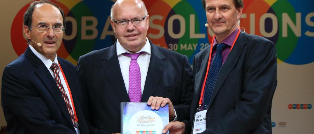 Gastgeber Dennis Snower (l.) und Dirk Messner (r.) übergeben die Empfehlungen der Thinktanks für die G20-Staaten an Kanzleramtschef Peter Altmaier (CDU).