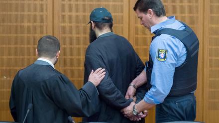 Ein Justizbeamter nimmt dem mutmaßlichen Islamisten Halil D. (M) am 21.01.2016 im Verhandlungssaal des Landgerichts in Frankfurt am Main (Hessen) die Handschellen ab, während sein Verteidiger Ali Aydin (l) ihm die Hand auf den Arm legt. 
