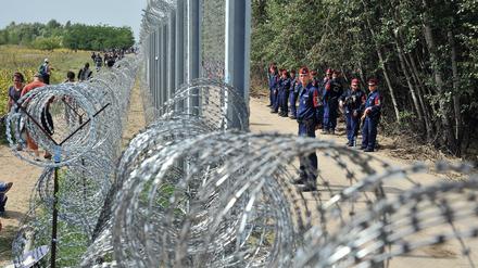 Hüben und drüben. Flüchtlinge laufen nahe der nordserbischen Stadt Horgos auf serbischer Seite an der mit Stacheldraht gesicherten Grenze entlang, an der auf ungarischer Seite Polizisten aufmarschiert sind. 