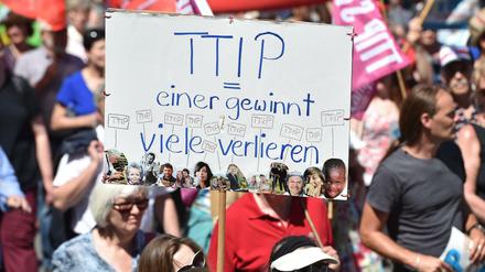 Demonstranten halten am 04.06.2015 in München (Bayern) bei einer Demonstration gegen den G7-Gipfel ein Schild mit dem Schriftzug "TTIP - einer gewinnt - viele verlieren". 