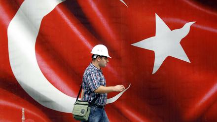 Ein türkischer Arbeiter vor einer riesigen türkischen Flagge. Erneut haben viele Staatsbedienstete ihre Jobs verloren. 