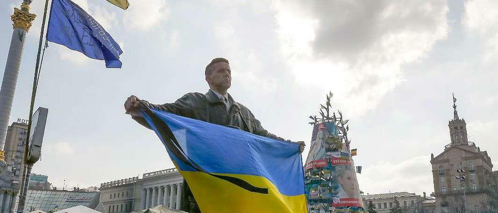 Ein Ukrainer hält während einer Trauerzeremonie die ukrainische Flagge hoch. 