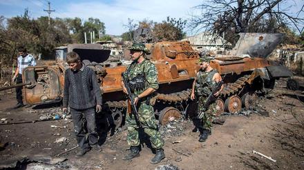 Prorussische Rebellen vor einem zerstörten ukrainischen Panzer.