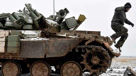Ein ukrainischer Soldat springt am Dienstag von einem in Kämpfen mit Separatisten stark beschädigten Panzer.