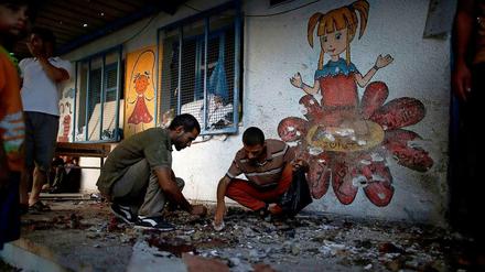 Palästinenser durchsuchen die von einer Granate getroffenen UN-Schule im Gazastreifen.